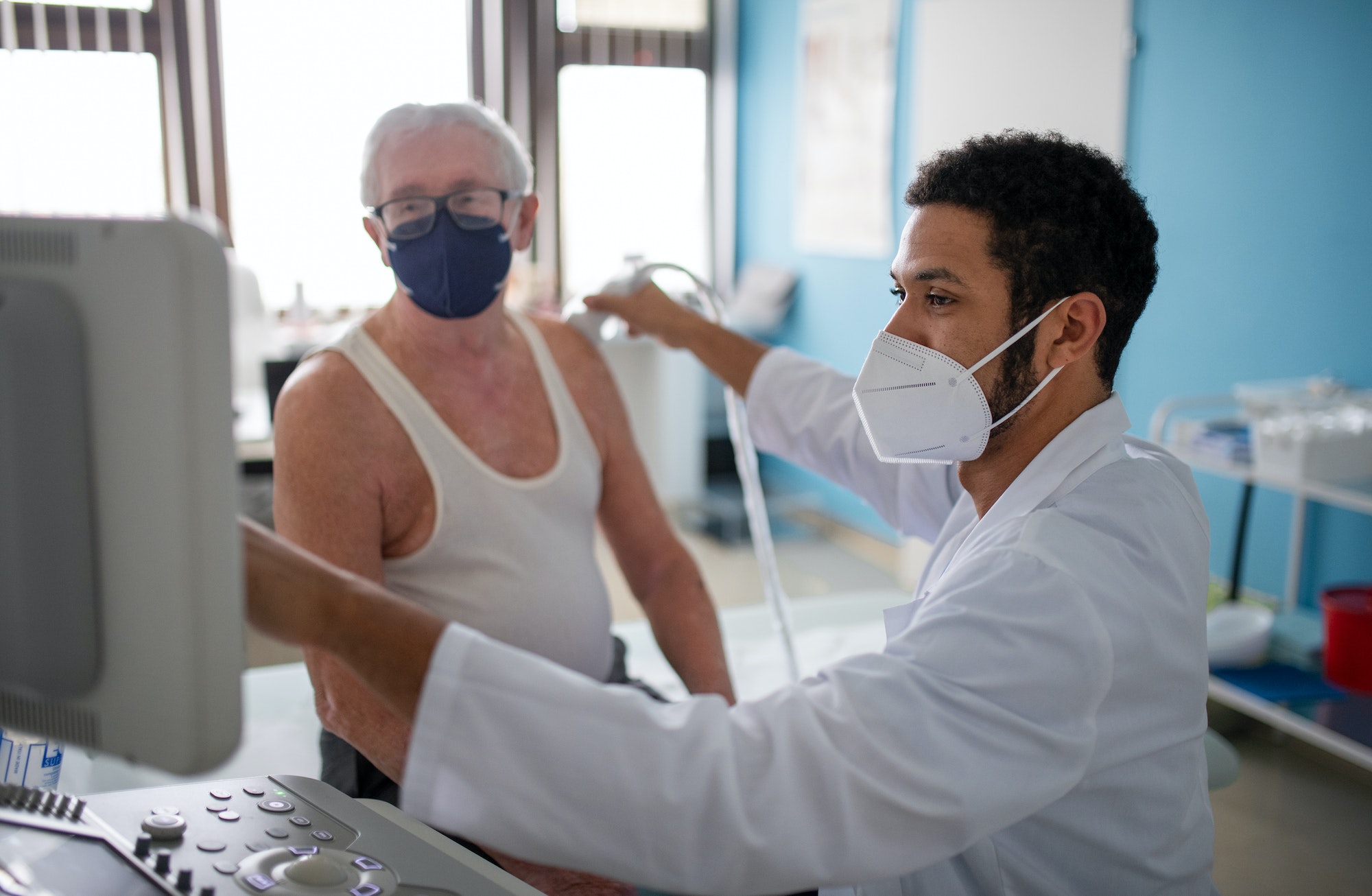 Young doctor is examining senior patient by using an ultrasound equipment in clinic